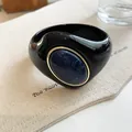 Detailed close-up of a bold black acrylic bangle with a marbled blue oval inlay - Geometric Open Style (10#)