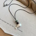 Detailed macro view of matte silver fish pendant necklace with black cord and rustic beads - #4 Necklace - Silver - Black - Small Fish