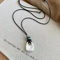 Macro view of minimalist silver teardrop pendant necklace with black cord and beads - #1 Necklace - Silver - Black - Oval