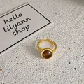 Detailaufnahme eines vergoldeten verstellbaren Rings mit bernsteinfarbenem Stein auf weißem Grund - Braunes Einzelstück (HR3682HR3792) / Gold