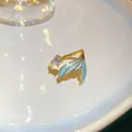 Detail view of a gold-toned mermaid tail ring with blue enamel and a clear zircon - Mermaid Tail Design (28#) / Gold Blue