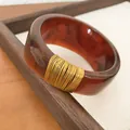 Macro view of the wide tortoise shell resin bangle featuring elegant gold wire wrap detail - Brown