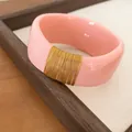 Detailed macro view of wide pink resin bangle with decorative gold wire wrapping - Pink