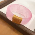 Close-up of pink marbled resin bangle with elegant gold wire wrap detail - Light Pink