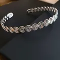 Vista dettagliata del girocollo in metallo argentato intrecciato con design a onde - Argento