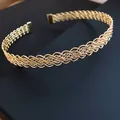 Vista dettagliata di un elegante girocollo in metallo dorato con motivo incrociato intrecciato. - Oro