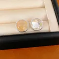Close-up of minimalist round silver stud earrings featuring natural yellow gemstones - Round Style / Yellow