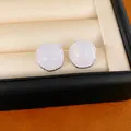 Macro view of round silver stud earrings with iridescent white stones in jewelry box - Round Style / White