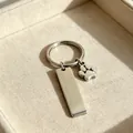 Vue détaillée d'une barre rectangulaire en acier inoxydable et d'un charme de patte de chien. - Acier