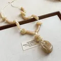 Gros plan détaillé d'un collier de perles en acrylique marbré beige avec pendentif - Style Grand Anneau Ajouré (48#)