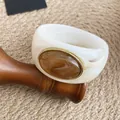 Gros plan détaillé d'un bracelet en acrylique blanc avec une incrustation d'ambre marbré chic - Ivoire-Café