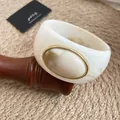 Vue détaillée du bracelet jonc en acrylique marbré avec un élégant insert ovale doré - Ivoire-Khaki