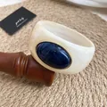 Vue détaillée d'un bracelet jonc en acrylique crème avec insert marbré bleu - Ivoire-Bleu