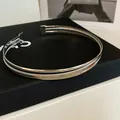Detaillierte Nahaufnahme eines silbernen Metallhalsreifs mit gewebter Textur und Finish - Kreuz Doppelring Stil (HN12908) / Silber