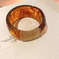 Detailed view of an amber acrylic bangle with elegant gold chain wrap and gradient texture. - Geometric Open Style (20#)