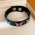 Gedetailleerd overzicht van een zwarte leren armband met veelkleurige vlinderbedels van strass - Vlinder Zirkonia / Zwart (Gekleurde Strasssteentjes)