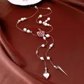 Detailed view of pearl beaded necklace with red apple pendant and heart tassel on silk fabric - Silver White Red