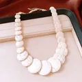 Macro shot of a white marbled stone beaded necklace showcased on a luxury jewelry tray - White