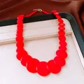 Macro view of the varying sized red circular stone beads on a designer necklace - Red