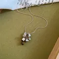 Close-up van een druivormige hanger met bruine stenen en zilverkleurige metalen bloembladen - Tijgeroog Druif-Zilver-Donkere Koffie