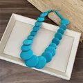 Detailed view of a vibrant chunky turquoise beaded round necklace on a white display tray - Blue