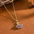 Primo piano di una collana con ciondolo a cigno con zirconi viola e catena dorata. - Collana T064 Cigno Dorato Viola