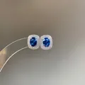 Close-up of royal blue oval stud earrings with sparkling double halo of stones - Light Blue Stud Earrings