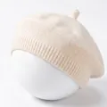 Detail van een crèmewitte gebreide babybaret met zachte textuur en klein steeltje. - Beige