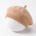 Detailed macro view showing the soft knitted texture and ribbed hem of a beige baby beret - Coffee