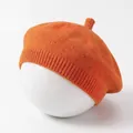 Close-up van een feloranje gebreide babybaret op een displaypop voor kinderen - Oranje