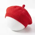 Close-up view of red knitted baby beret hat on white mannequin head - Red