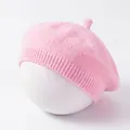 Close-up view of a soft pink knitted baby beret painter hat for early spring. - Pink