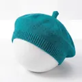 Gedetailleerde weergave van een blauwgroene gebreide babybaret op een witte voet - Saffierblauw