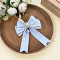 Detailed macro view of a light blue lace bow hair clip with an elegant pearl pendant charm - Blue