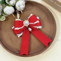 Macro view of a sweet red lace bow hair clip with a pearl pendant on a wooden tray - Red