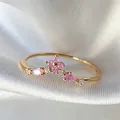 Elegant gold plated open ring featuring pink zircons on a white silk background - Adjustable Open / Pink Flower V-Shape (JZ065)