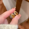 Elegant real gold-plated U-shaped earrings with amber zircon, showcased on fingers. - 13 Silver Post (Amber Zirconia Huggie) / Gold Brown