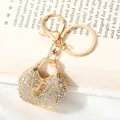Close-up of golden alloy handbag keychain with heart charm and sparkling rhinestones - White (YSK106BS035)