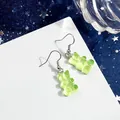 Primo piano di graziosi orecchini a forma di orsetto in resina verde chiaro su carta. - Verde