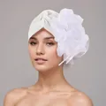 Primer plano detallado de un elegante turbante blanco con una gran flor de tela decorativa. - Talla única / Blanco