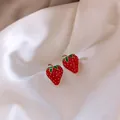 Détail en gros plan de jolies boucles d'oreilles fraises avec finition émaillée. - Rouge