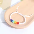 Primer plano de una pulsera trenzada blanca hecha a mano con nudos en colores del arcoíris - Blanco
