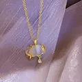 Close-up view of an elegant gold cloud necklace with lightning and crystal teardrop - Necklace / Gold