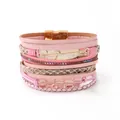Primo piano di un bracciale in pelle rosa multistrato con ciondolo a piuma dorata e chiusura magnetica - Stile Piuma Strass Sfumato (3) / Serie Rosa