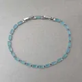 Gros plan d'un bracelet argenté délicat avec des pierres bleues claires rectangulaires. - Style Carré Bleu Clair Entièrement Sertis de Strass / Argent