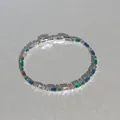 Nahaufnahme eines eleganten Silberarmbands mit lebhaften, bunten Kristallen im Baguette-Schliff. - Mehrfarbiger Quadratischer Vollstrass-Stil / Silber