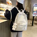 Vista posteriore di uno zaino color crema minimalista con accessori orso in un caffè - Modello Borsa Bianca