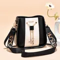Stylish black and white bucket bag with gold chain tassel and wide patterned strap - Black and White
