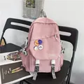 Large capacity pink laptop backpack for students featuring stylish decorative badges and white buckles - Pink
