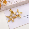 Elegant gold double starfish pendant featuring sparkling crystals and central pearl detail. - Starfish Pearl Pendant (XL795) / Gold